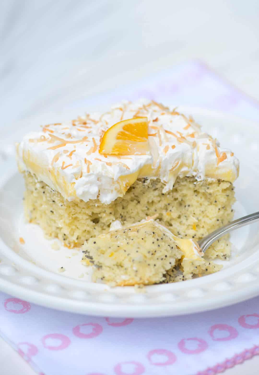 A slice of Lemon Coconut Poppy Seed Cake on a white plate with a fork.