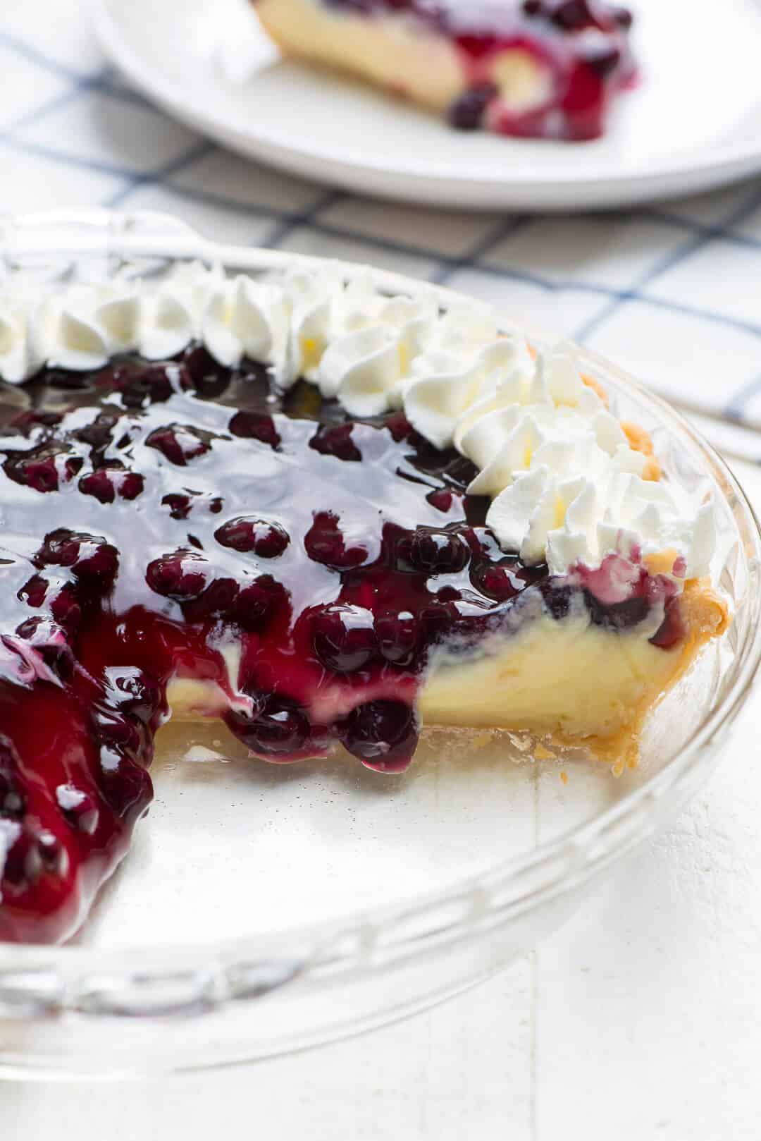 An image shot from the side of the pie with a slice missing and the blueberry filling draping down over the inside edge.