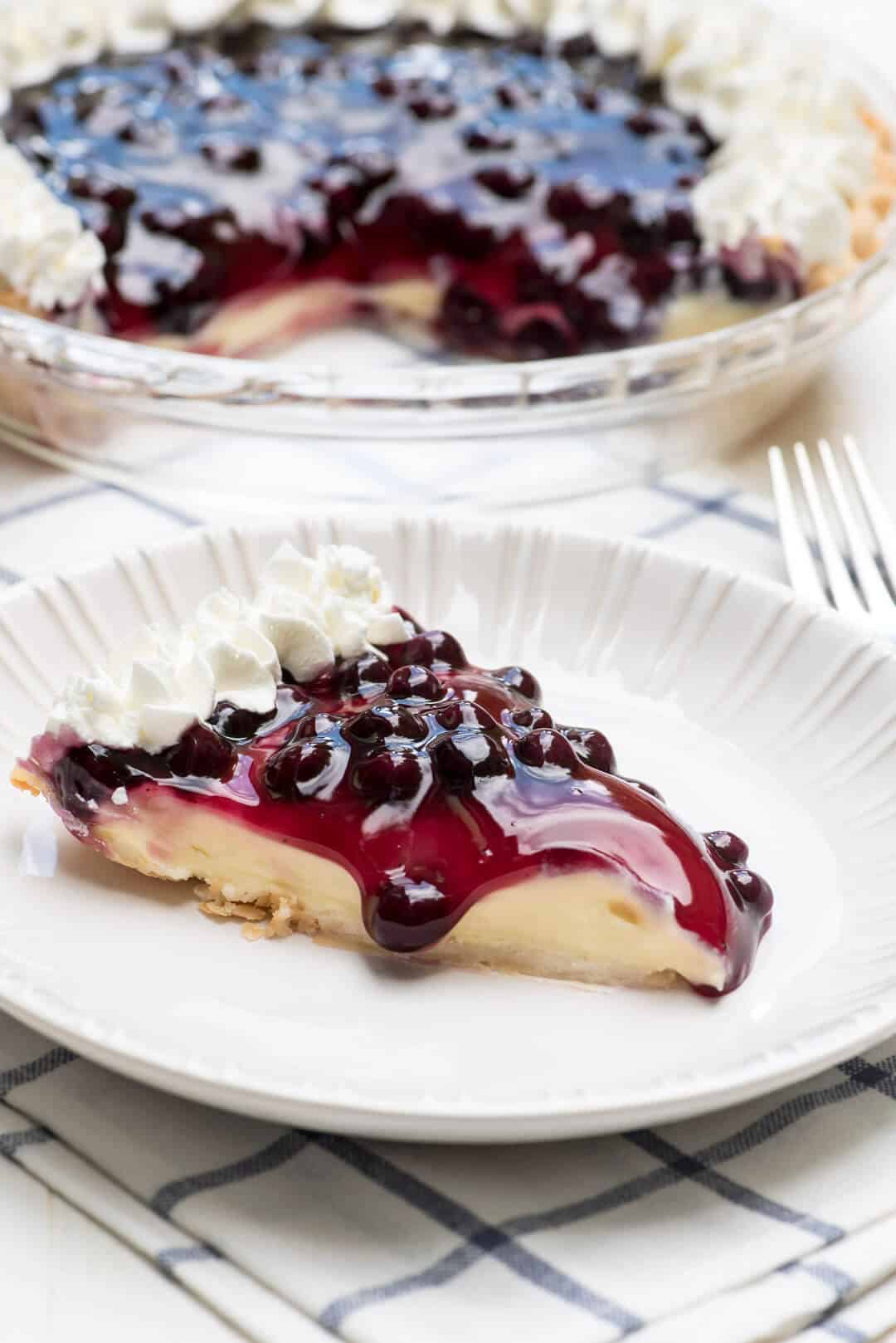 A slice of the pie on a white plate with the pie dish in the background.