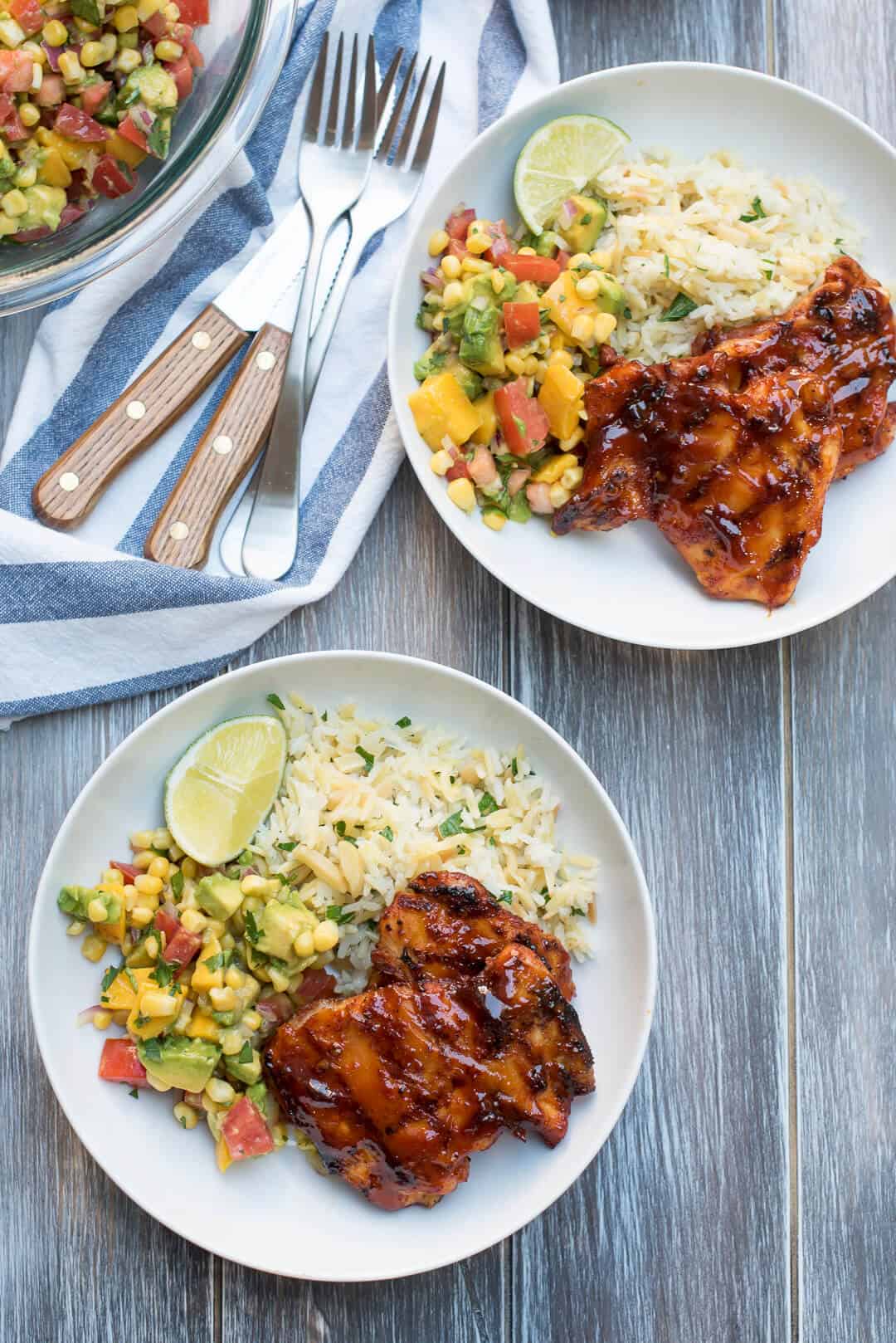 Two bowls filled with rice, fruit salsa and chicken.