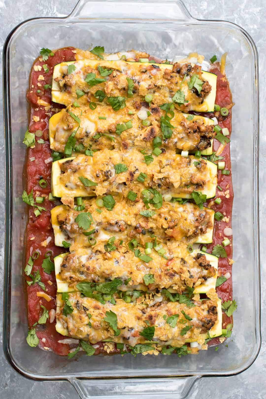 An overhead shot of a glass casserole dish full of Taco Stuffed Zucchini Boats.