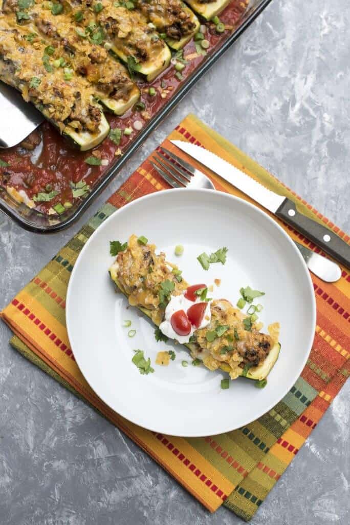 A zucchini boat with taco filling in a white bowl.