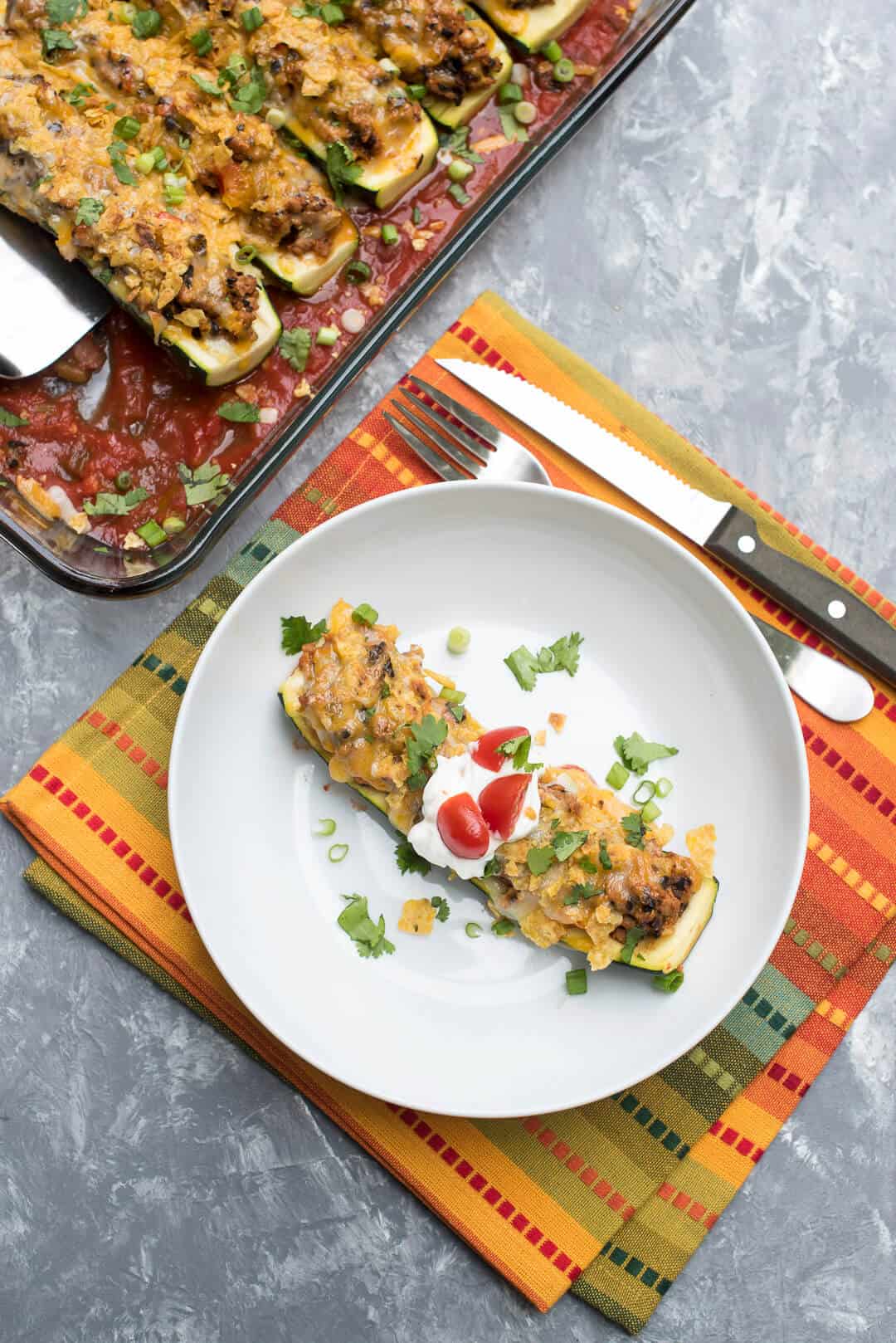 A zucchini boat with taco filling in a white bowl.