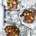 Sausage and potatoes in open foil packets.