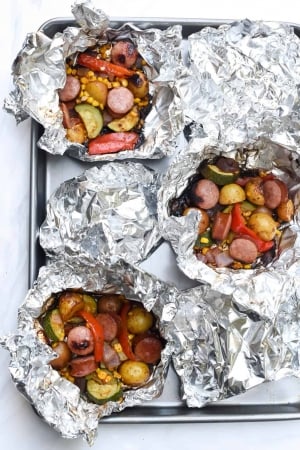 Sausage and potatoes in open foil packets.