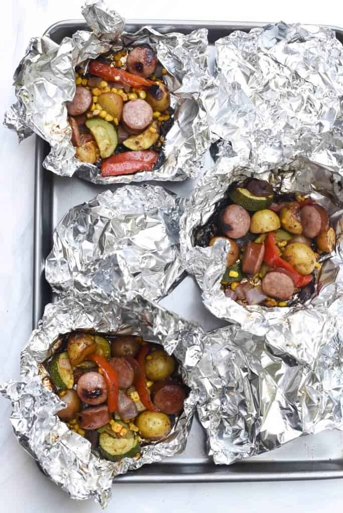 Sausage and potatoes in open foil packets.