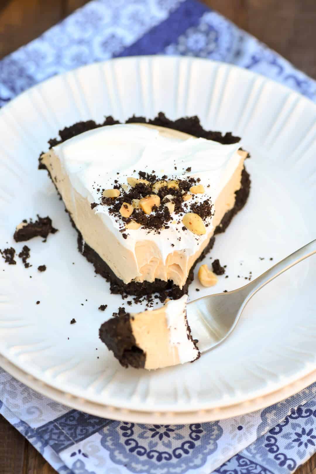 A slice of Frozen Peanut Butter Pie with a fork on a white plate.