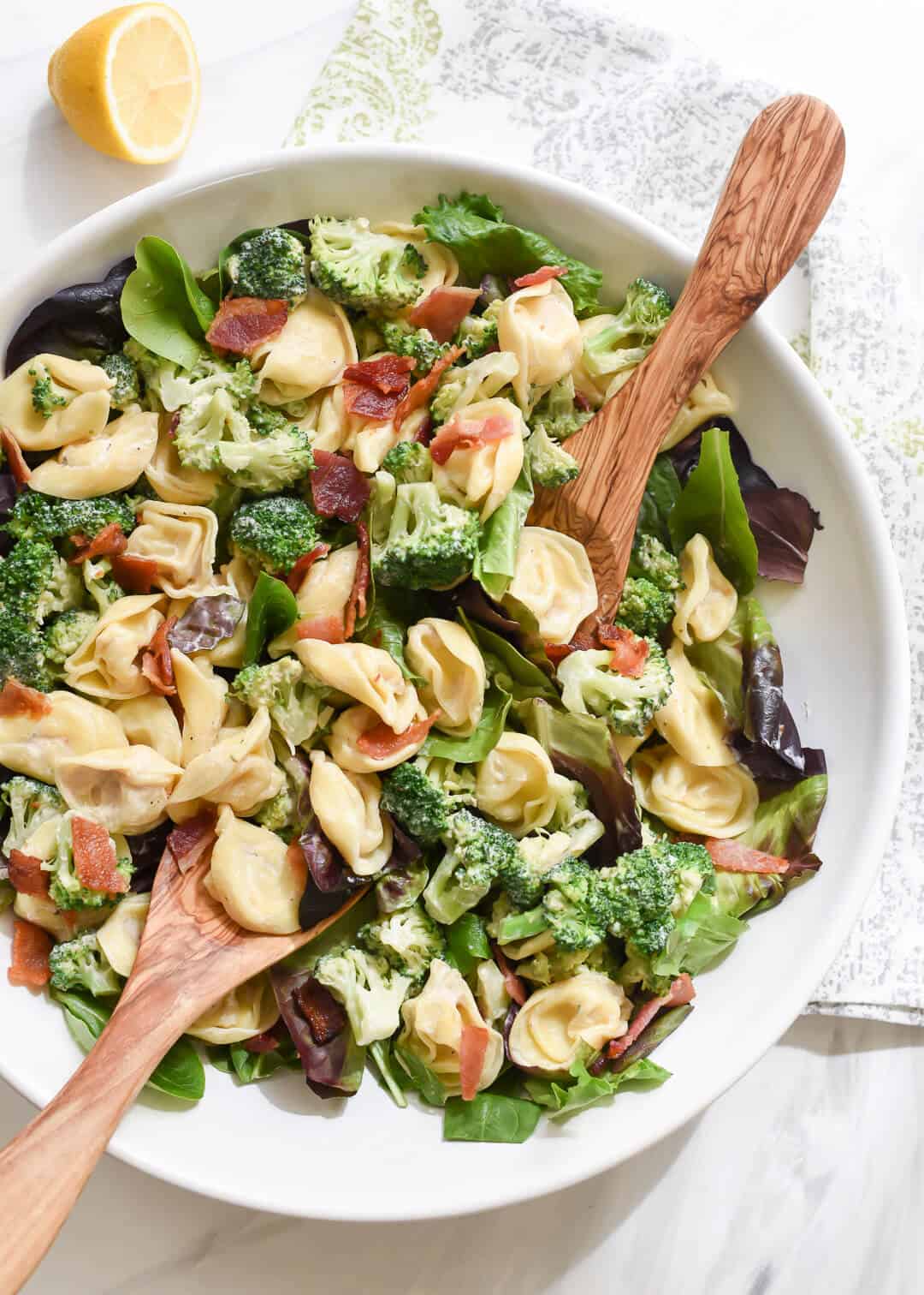 A bowl of spinach topped with tortellini and broccoli.