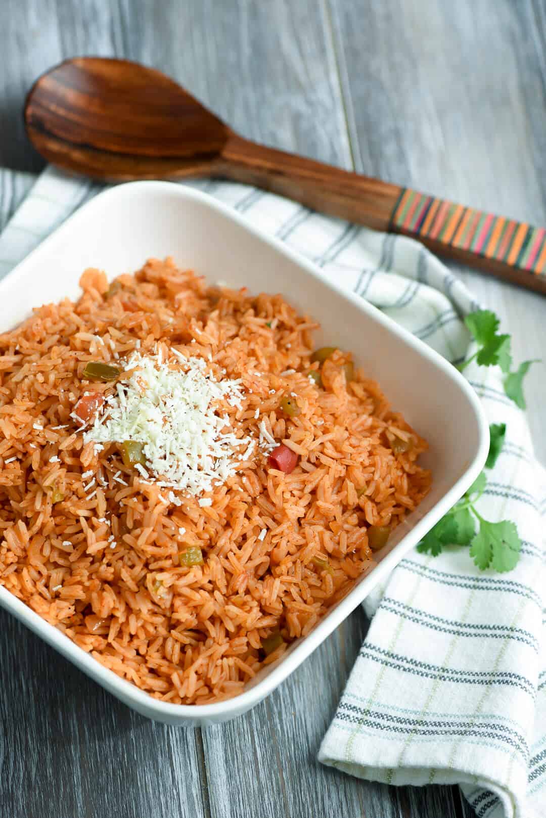 A white serving dish full of the rice on a striped kitchen towel.