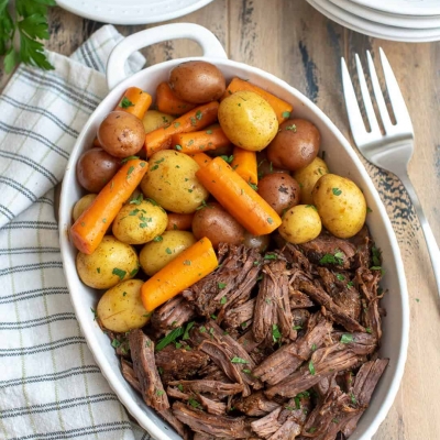 A white serving dish filled with shredded beef, carrots, and potatoes.