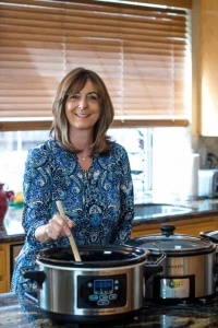 A woman preparing food in a slow cooker in a kitchen.