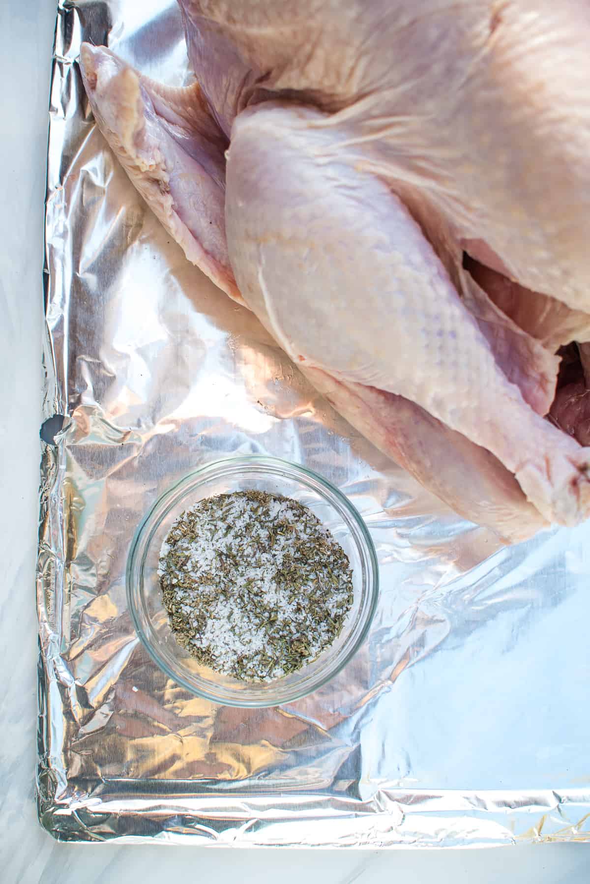 The dry brine ingredients combined in a small bowl next to the turkey.