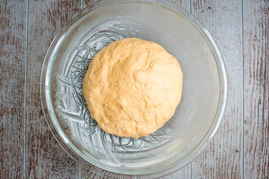 The ball of dough is transferred to a greased bowl to rise.