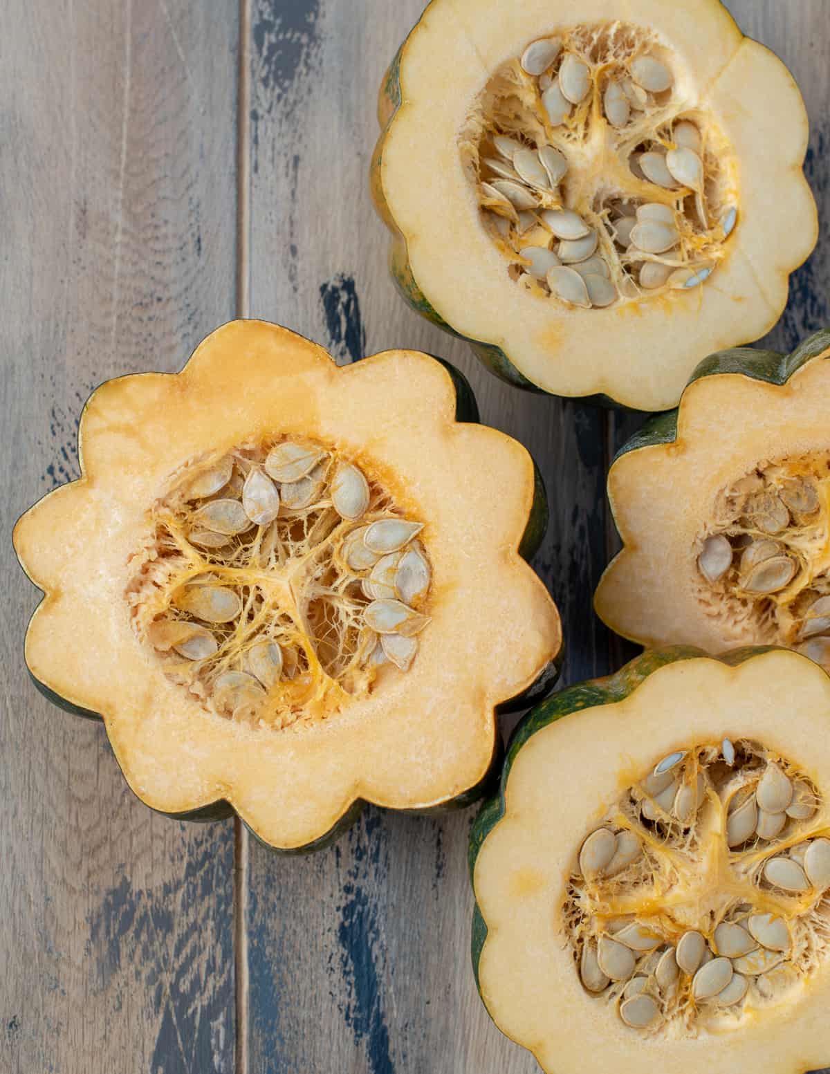 A top dpwm shot of acorn squash that have been sliced in half to reveal the seeds inside.