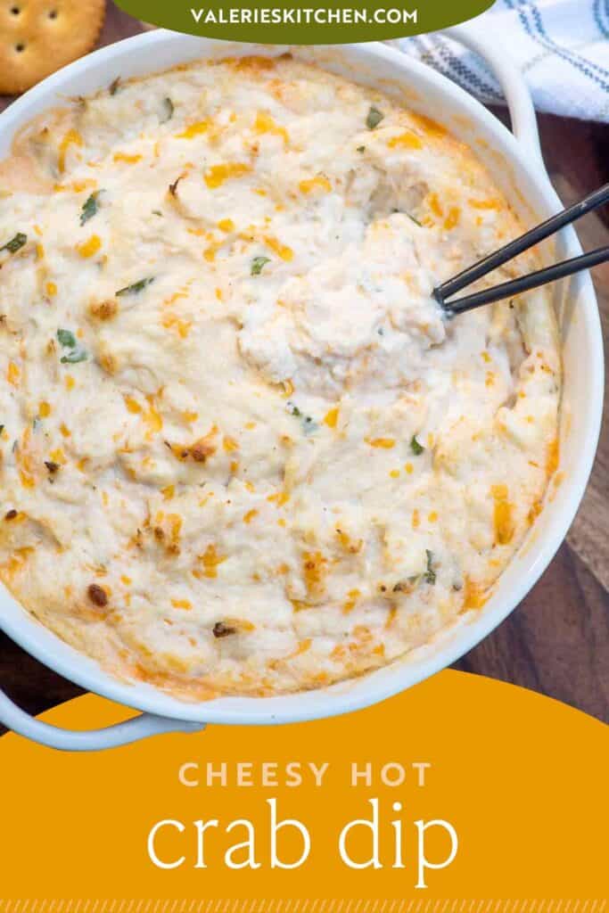 A small spoon resting in a bowl of warm crab dip with text overlay.
