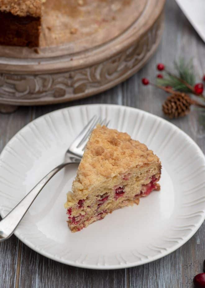 A slice of Cream Cheese Cranberry Coffee Cake on a white serving plate with a fork.
