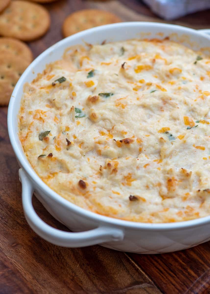 Crab dip in a white serving dish next to Ritz crackers.