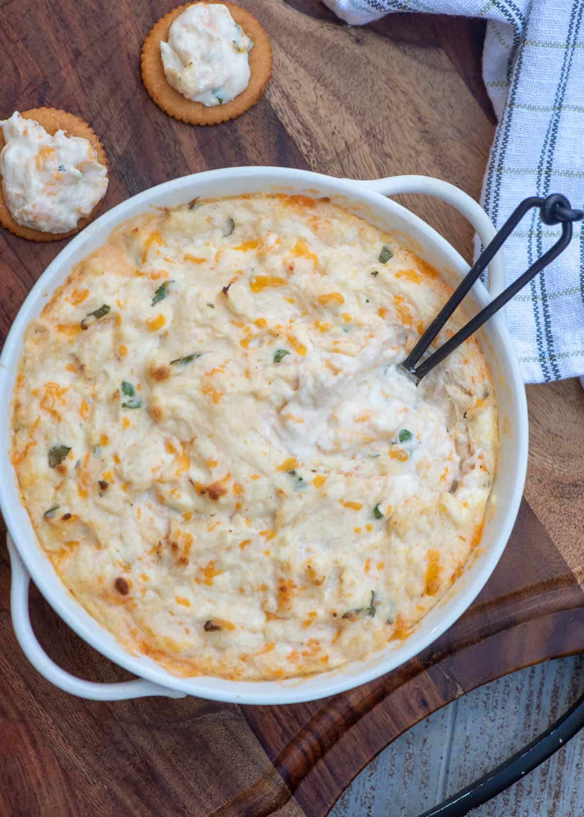 Ritz crackers topped with crab dip next to a white serving bowl with a small spoon.