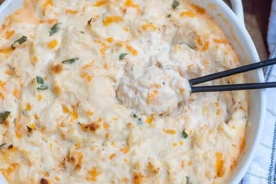 A white bowl filed with crab dip with a spoon.