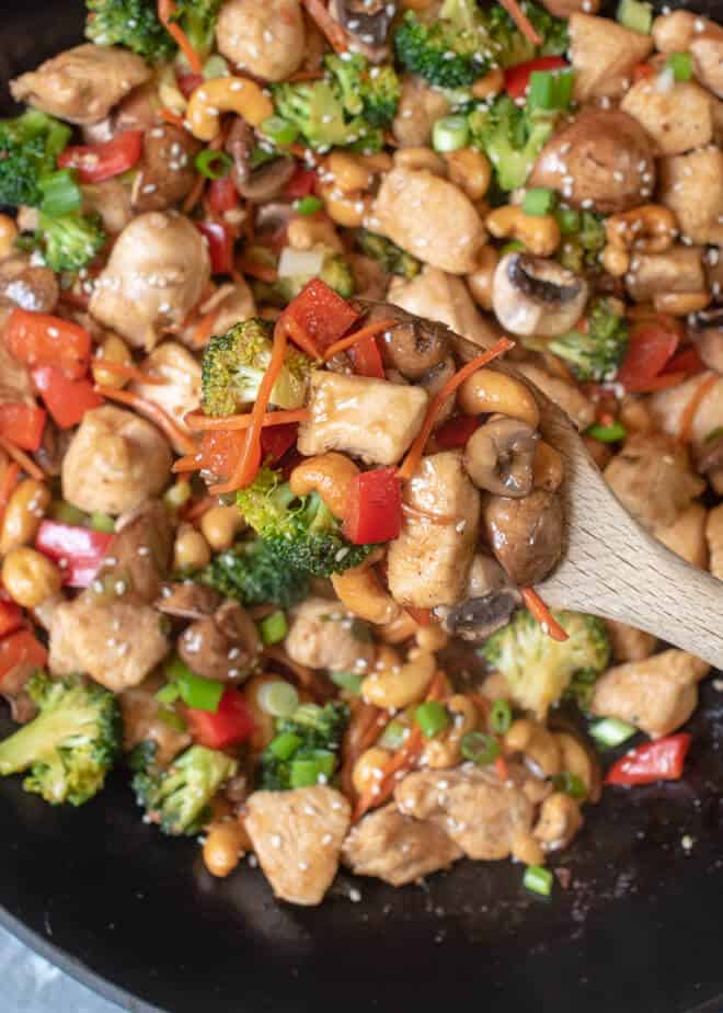 A very close up image of a spoonful of Cashew Chicken being lifted from the wok.