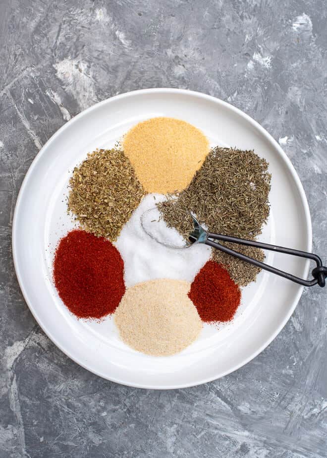 Spices and a small spoon on a white plate.