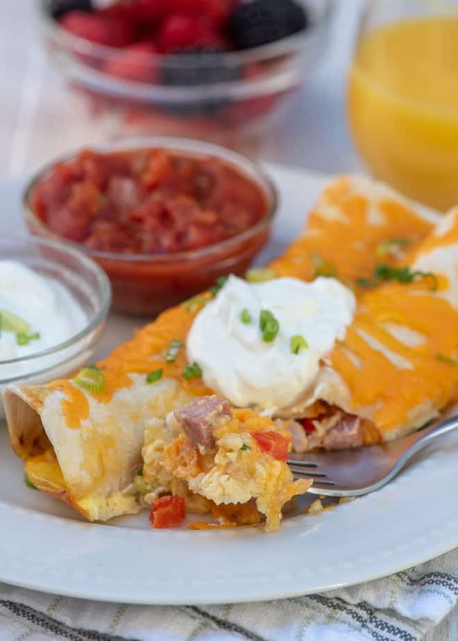 Ham and Cheese Overnight Breakfast Enchiladas on a white plate with a fork.