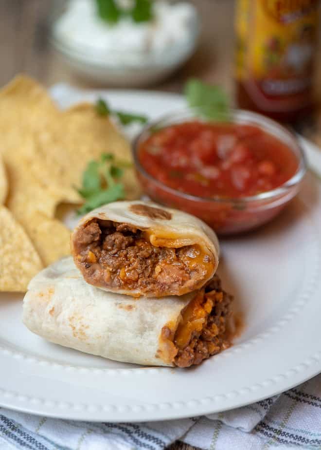 A Freezer-Friendly Beef and Bean Burrito cut in half and stacked on a white plate.