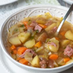 A spoon resting in a bowl of corned beef and cabbage soup.