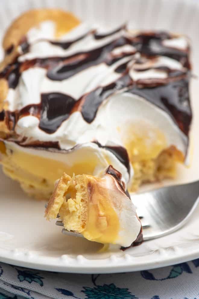 A close up shot of a slice of Easy Cream Puff Dessert with a fork breaking into it.