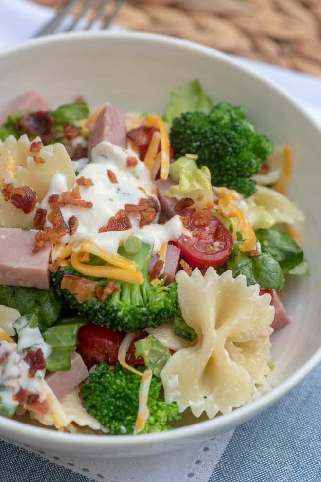 A single serving of Layered Ham and Broccoli Pasta Salad in a small white serving bowl.