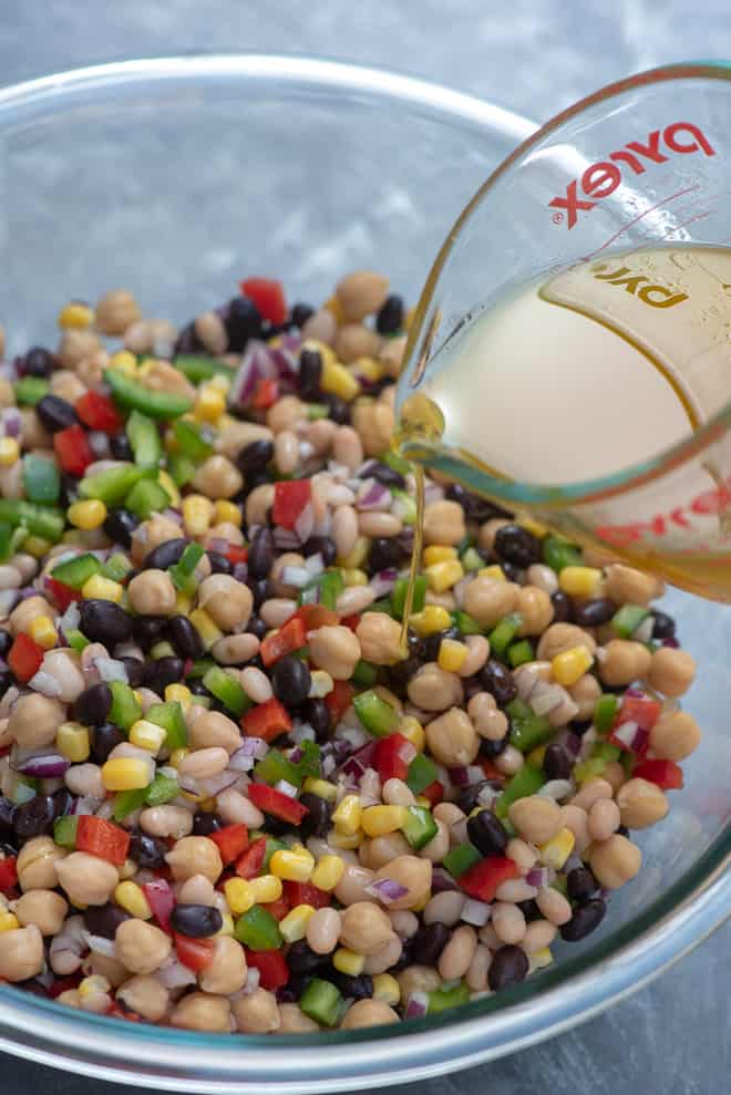 Pouring the dressing into the bowl of Mexican Three Bean Salad.