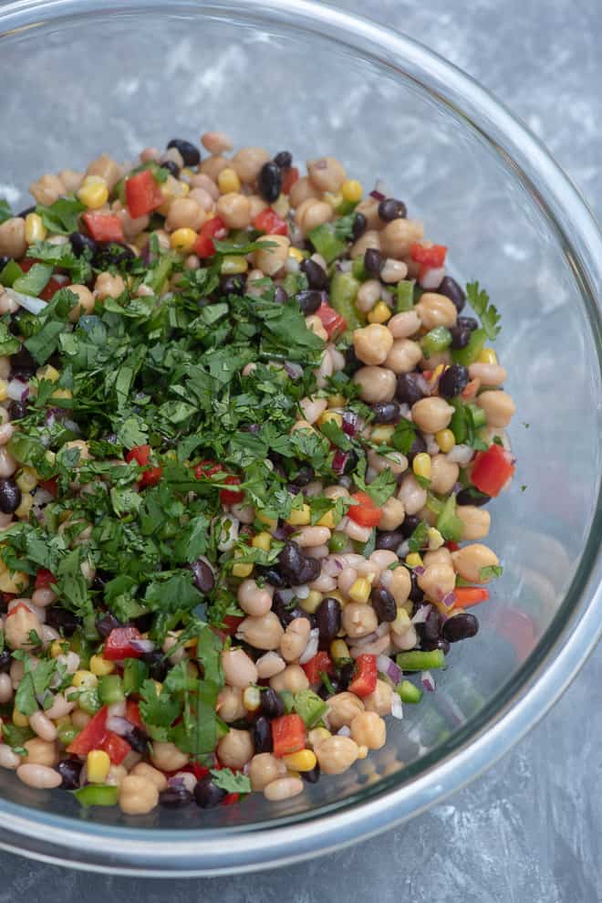 Mexican Three Bean Salad in a large glass mixing bowl topped with chopped cilantro.