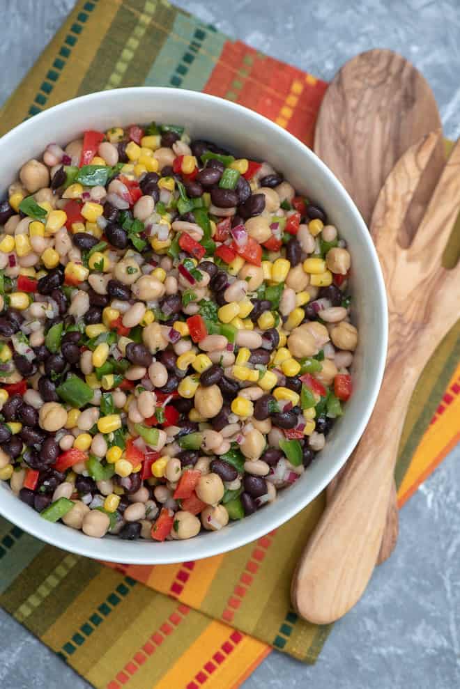 The finished recipe in a white serving bowl on a colorful cloth with wooden spoons off to the side.