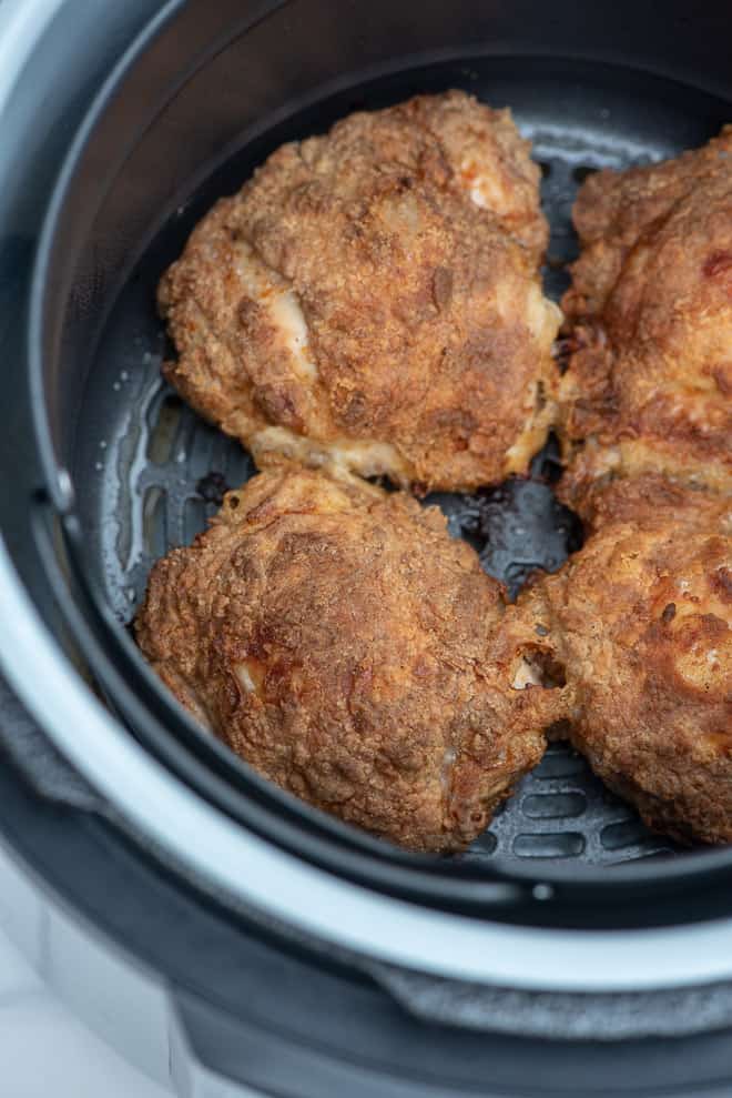 Four pieces of fried chicken in the air fryer insert.