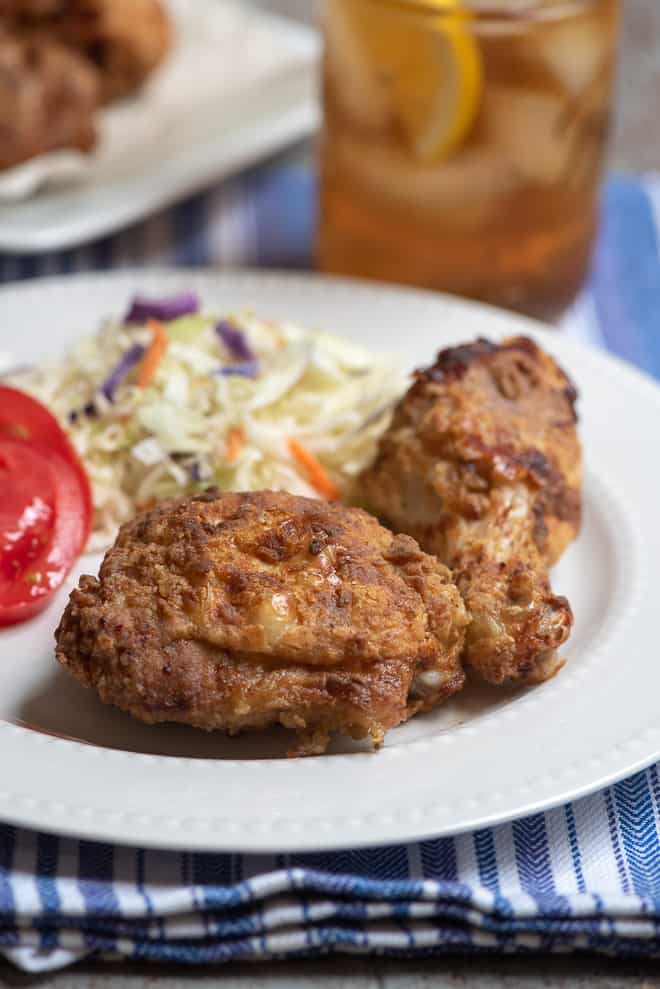 Two pieces of fried chicken on a white serving plate.