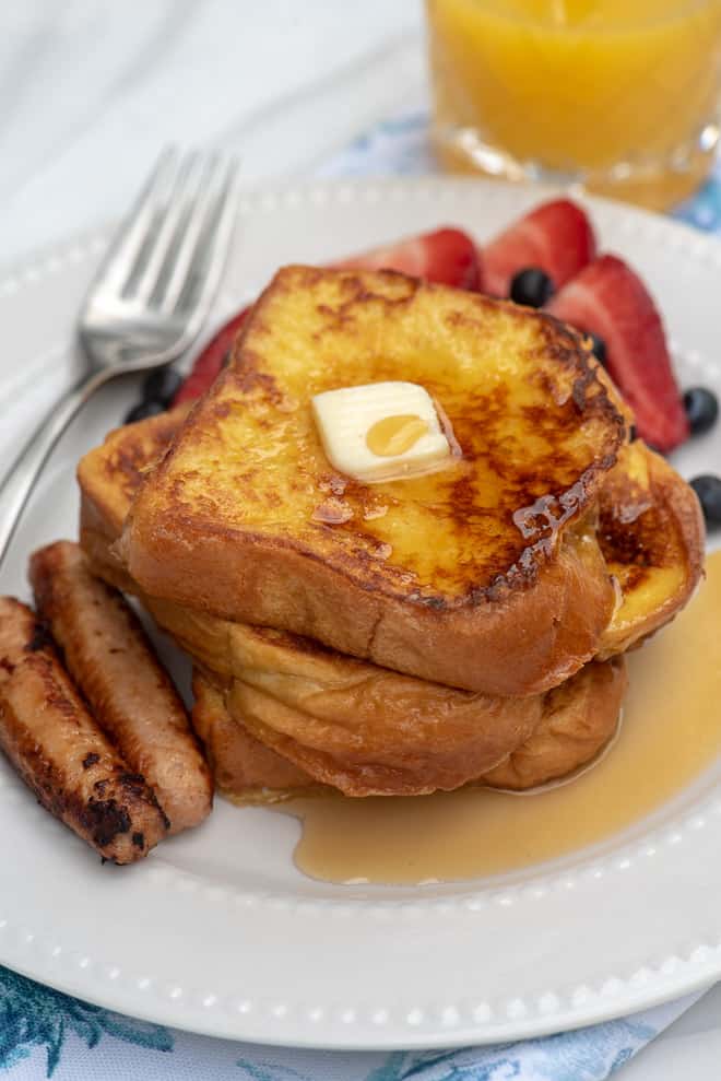 French toast op een wit bord met een klontje boter en ahornsiroop.