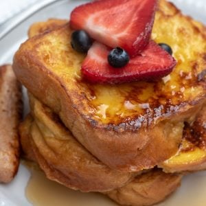 Eine Nahaufnahme von Brioche French Toast mit frischen Beeren und Ahornsirup.