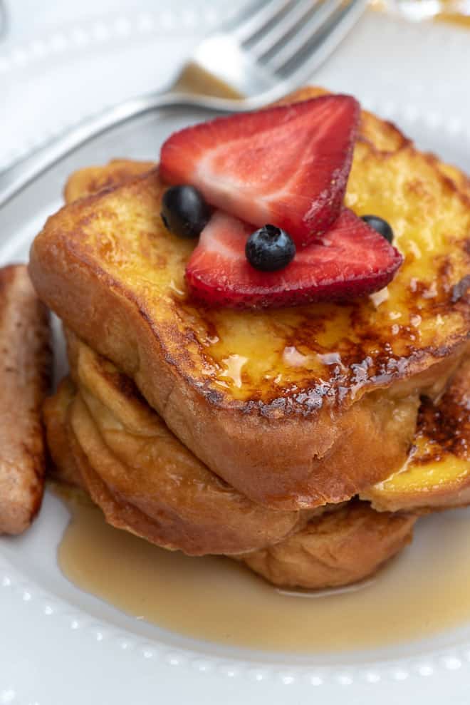 A close up shot of Brioche French Toast with fresh berries and maple syrup.