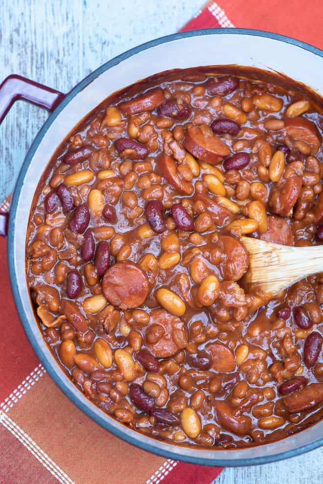 A Dutch oven full of kielbasa and beans from over the top.