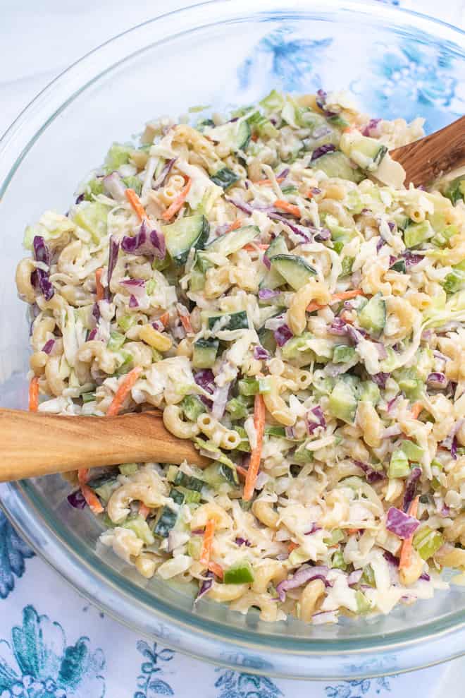 The salad from over the top in a glass serving bowl with wooden serving utensils.