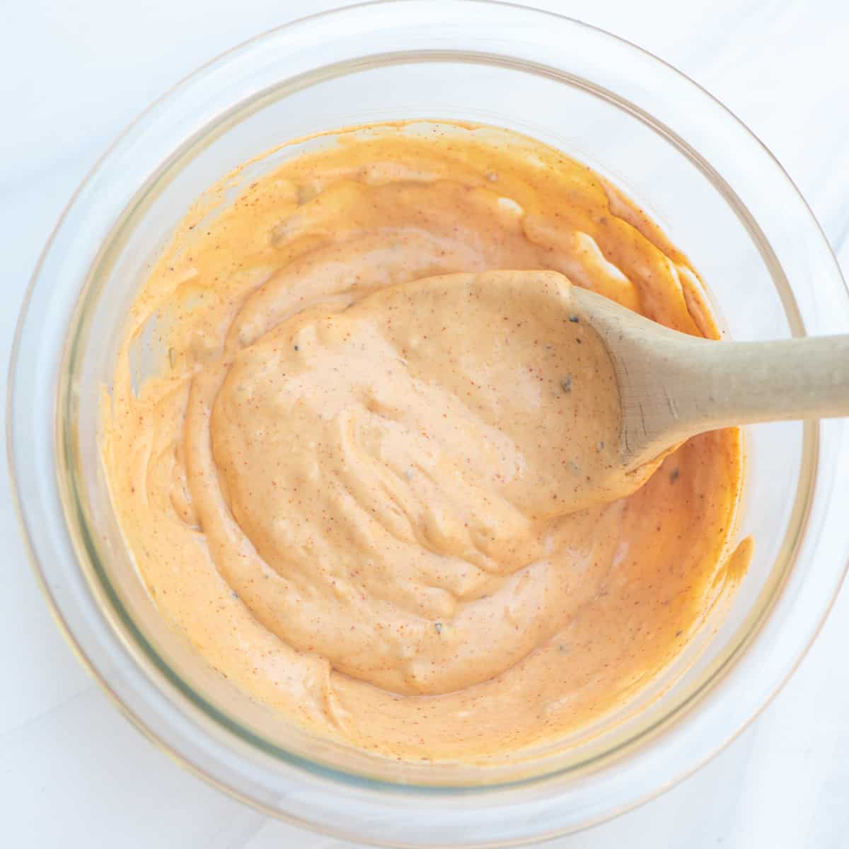 Burger sauce in a glass bowl with a wooden spoon.