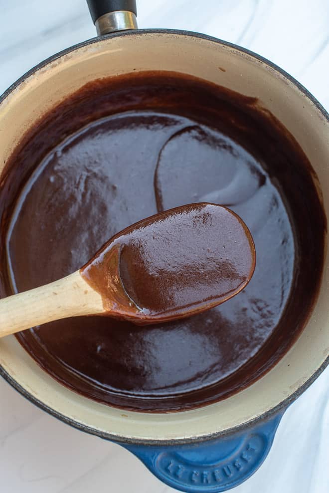 Chocolate Fudge Sauce in a blue saucepan with a wooden spoon.