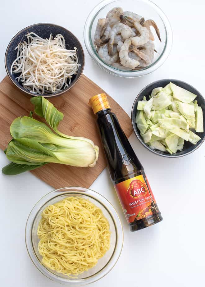 The ingredients - Sweet soy sauce (kecap manis), cooked yellow egg noodles, baby bok choy, bean sprouts, shrimp, and green cabbage.