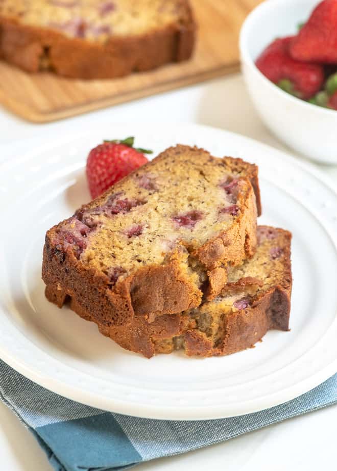 Two pieces of strawberry banana bread stacked on a white plate.