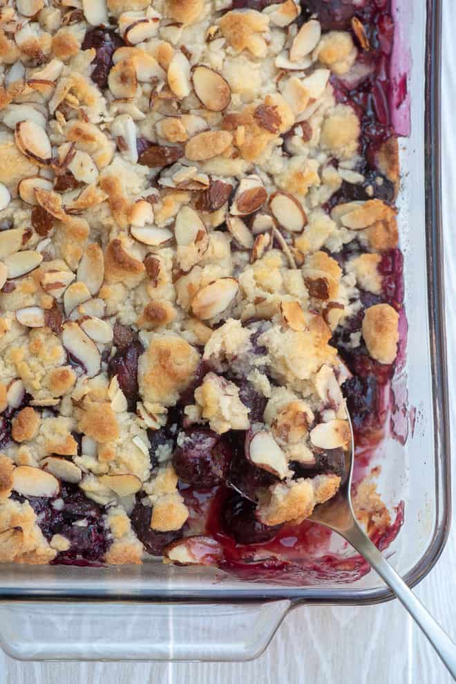An over the top image of Fresh Cherry Cobbler in a 13-inch x 9-inch baking dish with a serving spoon.