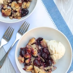 Two white bowls with ice cream and cherry cobbler.