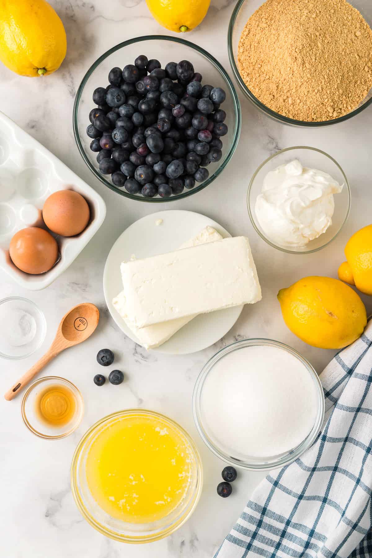The ingredients to make Lemon Blueberry Cheesecake Bars on a marble counter.