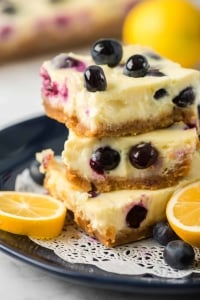 Cheesecake bars with blueberries stacked on a plate.