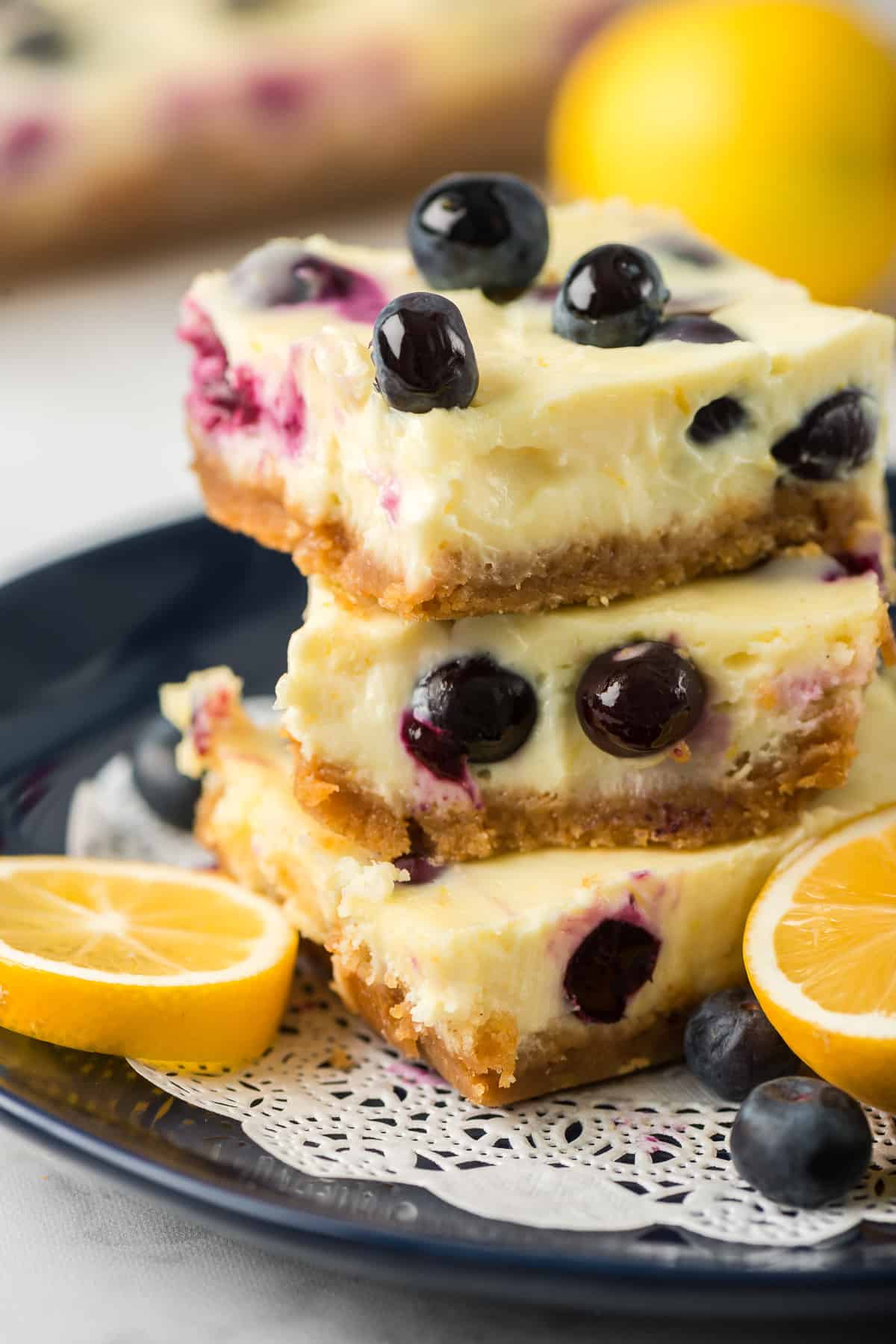 Cheesecake bars with blueberries stacked on a plate.