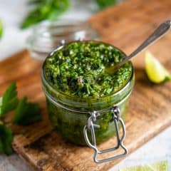 egy kőműves edény, amelyet Chimichurri mártással töltöttek egy vágódeszkán.